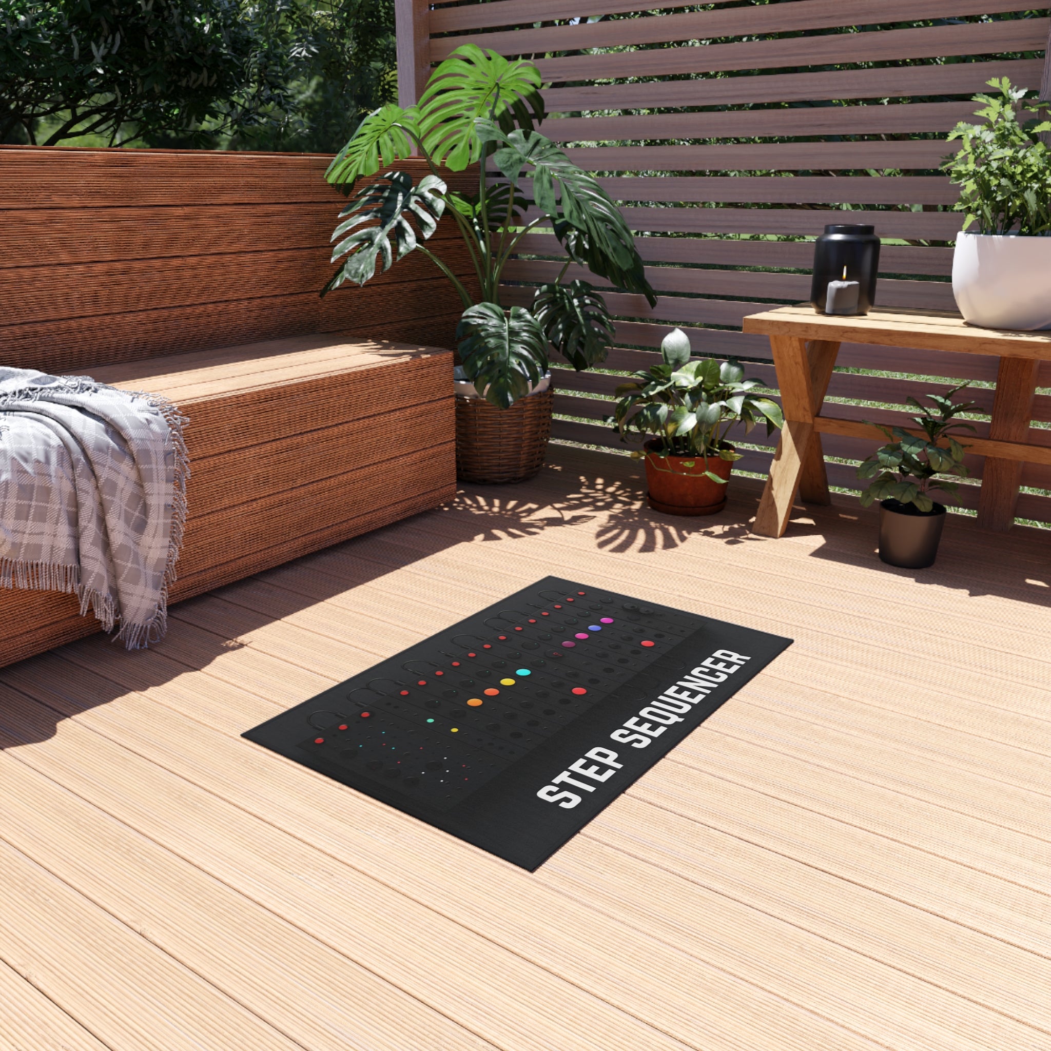 A large rectangular rug on a wooden deck features a detailed print of a synthesizer keyboard with the words 'USE THE FLOOR' printed below it, mimicking the design and layout of a classic musical keyboard. The rug is placed in an outdoor seating area with a cozy corner bench, a throw blanket, and potted plants, creating a relaxed and creative atmosphere